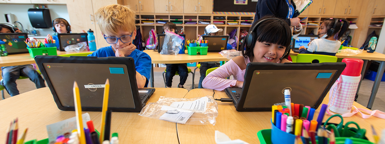 Elementary students work on laptops in a classroom.